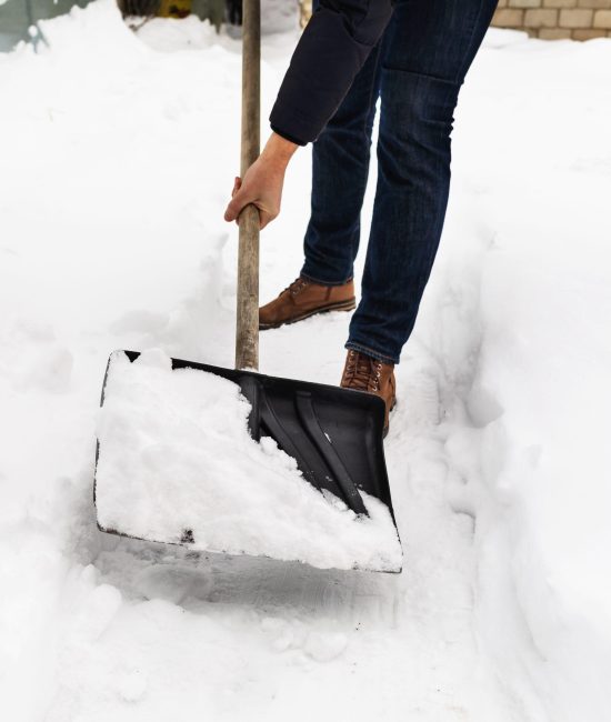 A man clears snow from paths on his property with a shovel A man clears snow from paths on his property with a shovel